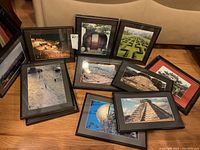Twelve framed architectural photography prints laid out on the floor, shown with mattes in dark frames. Includes images of ruins, gardens, and historic sites. Provides an overview of the complete lot.