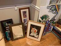 Group of framed artworks including dog pieces, boat drawing, western reproductions, and large colorful canvas.