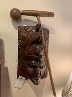 Polo mallet leaning on carved mask showing both items together