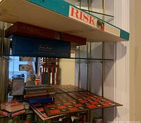 Shelf with Risk, Scrabble, Trivial Pursuit boxed games and a checker board laid flat