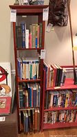 Front view of tall red painted wooden bookshelf filled with assorted books on four shelves. Books are not included in sale.
