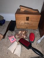 Full view of shoe shine kit, brushes, polish applicators, and wooden box with lid and latch visible