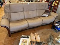 Frontal view of three-seat beige leather sofa with small pillow on right seat