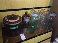 Overall view of stoneware crock, sealer jars, and assorted bottles on countertop