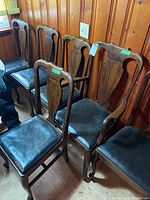 Six oak chairs clustered against wood-paneled wall