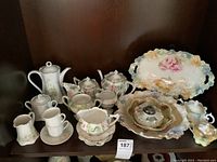 Upper shelf display of assorted porcelain pieces on wood background