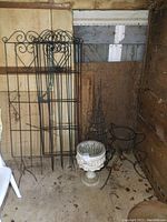 Full view of 4 metal trellis panels, resin urn planter, tomato cages and metal planter stand grouped together in corner of shed