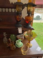 Overview of entire lot on wooden surface showing lamps, bowls, cruets and pitcher