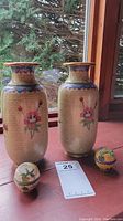 Two metal cloisonné vases and two small cloisonné bowls with lids displayed on a windowsill showing overall lot