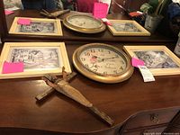 Photo displaying the entire lot including clock, cross, two framed prints, and faux orchid on wooden surface