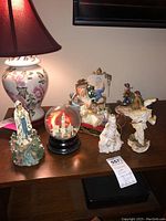 Seven figurines grouped on a wooden table including snow globe and various statues.