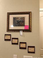 Wide shot showing framed print with four smaller inspirational tiles arranged below in a stair-step layout on a beige wall.