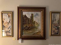 Three framed urban scene paintings including one large signed J. David and two smaller pieces; all in gold carved frames