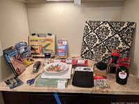 Overview of lot showing multiple office and household items arranged on shelf including the Avon Christmas plate near center
