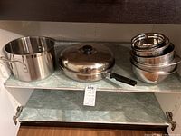 Wide shot showing 16-quart pot, covered pan, and 9 nested stainless steel bowls on shelf.