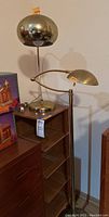 Floor lamp and table lamp side by side on top of corner bookshelf