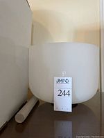 Front view of white frosted crystal singing bowl and mallet alongside a white box