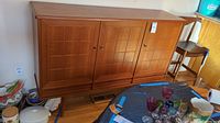 Front view of teak buffet showing three panel doors and tapered legs
