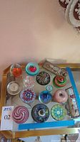 Overview of all spherical paperweights and two rectangular prism boxes on glass table