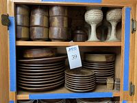 Cabinet shelves displaying mugs, goblets, dinner plates, salad plates, saucers, salt and pepper shakers