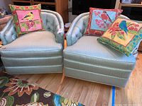 Pair of pale green tufted barrel arm chairs with three colorful bird-themed throw pillows on and around them, showing overall lot contents.