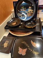 Black lacquer round tray with Asian mountain landscape, black trays with butterflies and owl, wood trays and small bowls stacked