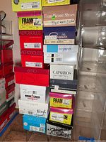 Stack of shoe boxes including Aero, Minnetonka, EasySpirit, Keds, Caparros, and Franconia with several white plastic organizer boxes stacked beside them.