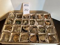 Top view of all 24 mineral specimens arranged in individual boxes with identification papers inside each box.
