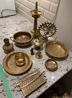 Overview photo showing the full assortment of brass items on a countertop: bowls, a Shiva figure, candle holder, jewellery box, letter openers, and a small vase.