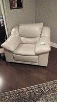 Front view of the cream leather armchair showing cushioned arms, seat, and backrest.
