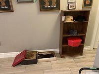 Three men's hats, two cardboard hat boxes with lids, and a pair of women's boots on floor, some hats on shelving