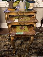 Full stacked view of three nesting tables with floral painted tops and curved legs in shabby chic style.