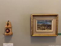 Wall view showing one oil painting in gold frame and one wooden key holder with copper element.