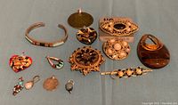 Full view of entire jewelry lot displaying bracelets, brooches, pins, and various pendants in different colors and styles.