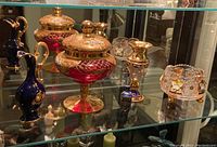 Overview of all porcelain, glass and metal items displayed on a glass shelf