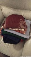 Stack of scarves folded showing various colors including burgundy with design, gray, green, navy