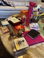 Grouped assortment of stationery, decorative boxes, and souvenirs arranged on marble table.
