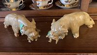 Pair of carved stone lions with prey, displayed on a wooden surface with china cups in the background.