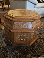 Side and top view showing detailed inlay and carved accents on wood octagonal table.