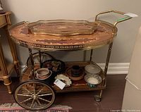 Front perspective of tea cart with tray on top and decorative items on lower shelf