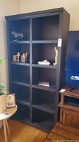 Front view of the wooden cubby style bookcase with multiple compartments and some decorative items placed in a few cubbies.
