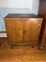 Front view of wooden cabinet showing brass hardware and raised legs