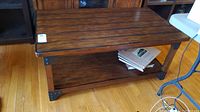Front angle view of wooden coffee table with plank top and metal corner supports.