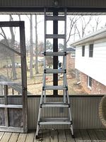 Full view of the aluminum multi-position folding ladder in open position showing stair-step design and structural frame.