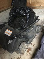 Front left wheel and deck partially covered by storage bag