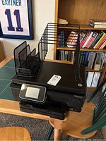 HP Photosmart 6520 printer stacked with two different black metal filing organizers on top on a wooden table.