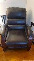 Front view of brown faux leather recliner chair showing padded backrest, seat and wooden arms
