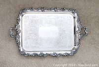 Full top view of the large Birks silver plated serving tray laid flat on carpet showing the engraved floral and scroll pattern with decorative ornate border and handles.