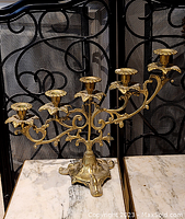 Full frontal view of the brass candelabra showing all five candle holders and decorative base.