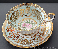 Close-up of Paragon porcelain cup and saucer showing blue background, gold ornate detailing with crown motif, ER initials, and floral center
